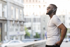 Cheerful african guy in headphones enjoying listening to music